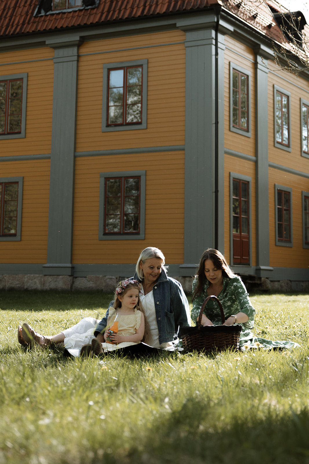 Familj på picknickfilt framför herrgården